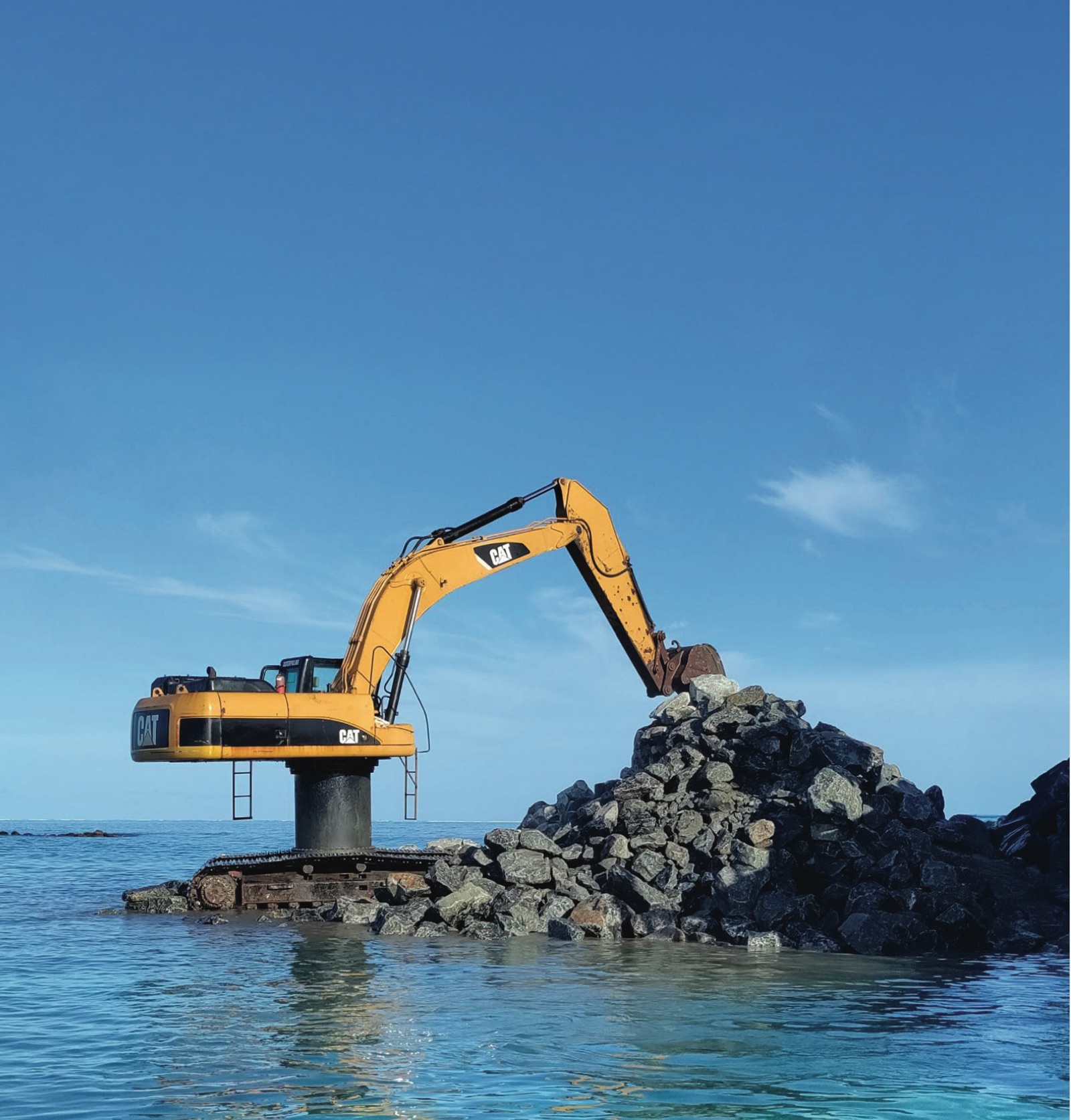 Tracked excavator working on a rock revetment at the water's edge